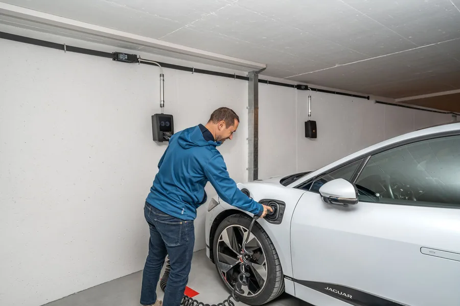 Man som kopplar in en elbil i en laddbox i ett garage